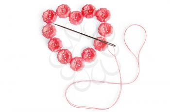 The heart of the pink buttons with needle and pink thread isolated on white background