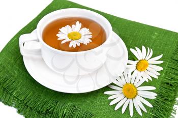 Herbal tea in a  white cup with daisies on the green napkin, isolated on a white background