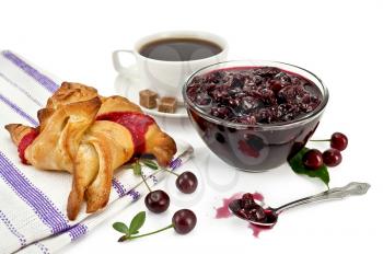 Cherry jam in a glass bowl, spoon, cherries with green leaves, white porcelain cup with coffee, two lumps of sugar, bun with jam on a napkin isolated on white background