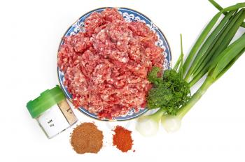 Minced meat on a plate with onions and spices isolated on white background