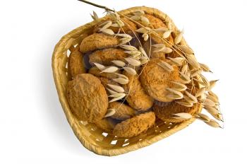 Oatmeal cookies in a wicker basket with a stalk of oats from above isolated on white background
