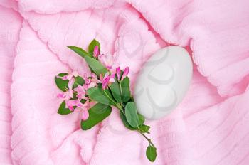 White soap, a branch with pink flowers and green leaves on a pink towel
