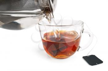 Tea from a bag in a glass bowl, teapot with hot water isolated on white background