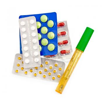 The thermometer in the case of multi-colored pills and capsules in packs isolated on white background