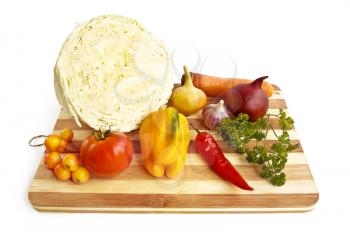 Half of the cabbage, yellow and purple onion, carrots, garlic, parsley, hot red pepper, sweet yellow peppers, apples, tomatoes on a wooden board isolated on white background