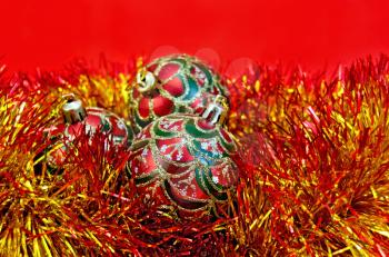 Three red Christmas ball with a pattern in red and gold tinsel on red background