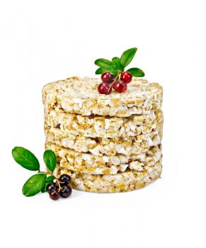A stack of cereal crispbreads and sprigs of leaves and berries with lingonberries isolated on white background