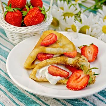 Pancakes with strawberries and cream, a basket of berries, bouquet of daisies on a striped linen napkin