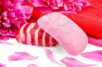 Soap and towels pink and red with petals and peony flowers isolated on white background