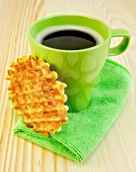 Round golden waffle, a green mug on the green napkin against a wooden board