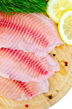 Tilapia fillets with dill, lemon and pepper on a wooden board isolated on white background