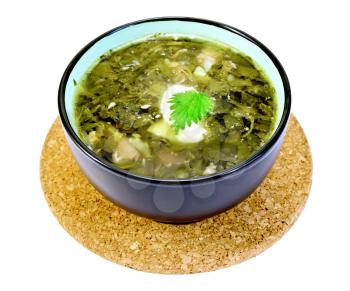 Green nettle soup in a bowl on a stand cork isolated on white background