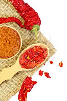 Red pepper powder in a wooden bowl, cereal and pods of red pepper on a napkin from a sacking isolated on white background