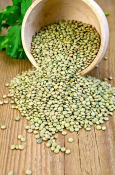 Green lentils in a wooden bowl with parsley on a wooden boards background