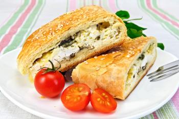 Roll layered with spinach and cheese, tomatoes in a plate on a linen tablecloth background