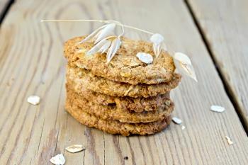 Stack of oatmeal cookies with cereal and a stalk of oats on the background of wooden boards