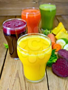 Four tall glass juice from carrot, cucumber, beetroot and pumpkin, vegetables on background of wooden boards