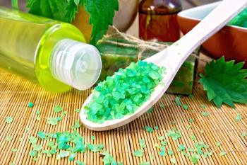 Green salt, shampoo, oil, gel, soap with nettles in a mortar on a wooden boards background
