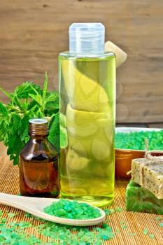 Shampoo, oil, gel, salt, soap with nettles in a mortar on a wooden boards background