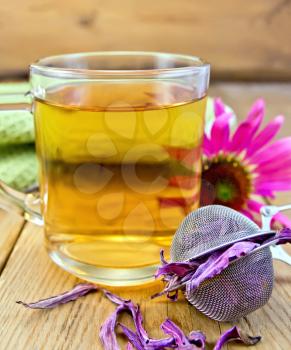 Herbal tea in a glass mug, metal sieve with dry flowers echinacea, echinacea fresh flowers on the background of wooden boards
