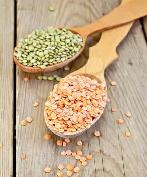 Red and green lentils in a wooden spoon on a wooden boards background
