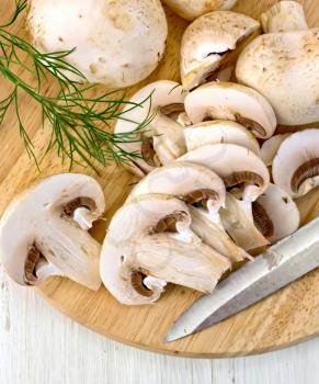 Champignons raw whole and sliced with a knife and a sprig of parsley on a wooden board
