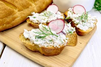 Bread with pate of cottage cheese, dill and radish on a wooden board, a napkin on a background of a wooden table