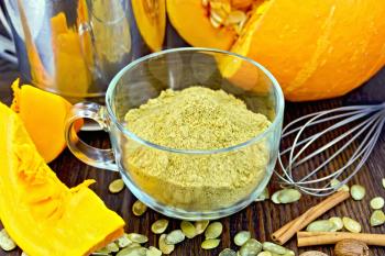 Flour pumpkin in a glass cup, sieve, mixer and cinnamon, cloves fresh pumpkin, pumpkin seeds on the background of wooden boards