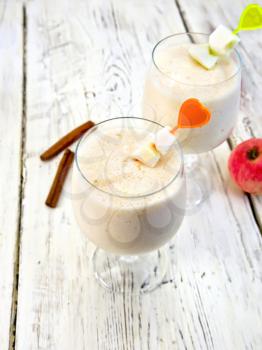 Jelly airy apple in wineglasses, red apples and cinnamon on a background of wooden boards