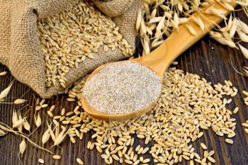 Bran flakes oat in spoon, a bag of grain oats, oat ears on the background of wooden boards