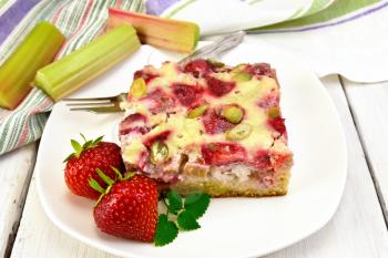 Piece of pie with strawberries, rhubarb and cream sauce, fork, strawberry, mint in white plate, napkin on a wooden boards background