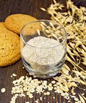 Bran small oat in a two glassful, oatmeal and ears, cookies on a background of wooden boards