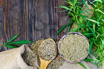 Flour in a bowl and hemp seeds in a spoon, green twigs of cannabis on sackcloth background on wooden board
