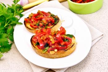 Bruschetta with roasted tomatoes, peppers, garlic, onions and parsley in a plate on a towel on the background of a granite table