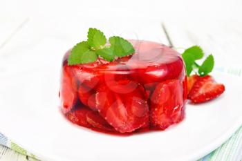 Strawberry jelly with mint and berries in a plate on a napkin against the background of wooden boards