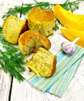 Pumpkin Scones with garlic and dill on a napkin, yellow pumpkin slices on the background light wooden boards