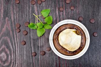 Cake with chocolate and pear in a white bowl, mint on the background of wooden boards top