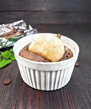 Cake with chocolate and pear in a white bowl, mint on the background of wooden boards