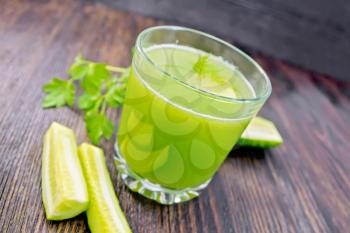 Cucumber juice in a glassful, vegetables and parsley on a background of a dark wooden board