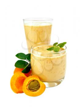 High and low glassful with a milky apricot cocktail, fruit isolated on a white background