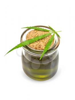 Hemp oil in a glass jar with a sheet on a lid isolated on a white background