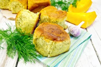 Pumpkin Scones with garlic and dill on a napkin, yellow pumpkin slices on the background of wooden boards