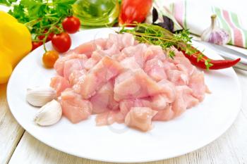 Sliced chicken breast with garlic, hot pepper and thyme in a plate, napkin, parsley and vegetables on a wooden board background