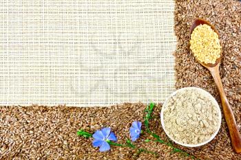 A frame of brown and white linseed, flax flour in a bowl, blue linen flowers against a rough woven fabric background