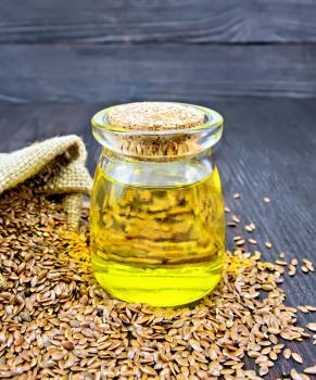 Linseed oil in a glass jar with seeds in a bag and on a table on the background of a wooden board