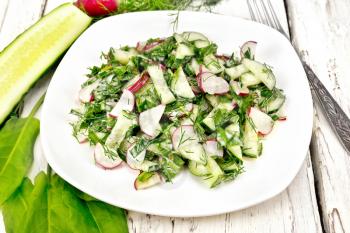 Salad of radish, cucumber, sorrel and greens, dressed with mayonnaise in a plate on the background of light wooden board