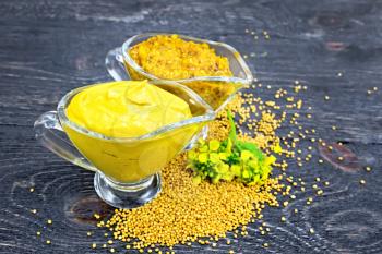 Mustard sauce and Dijon mustard in two glass saucepans, yellow flower and seeds against the background of a wooden board