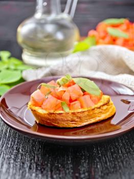 Bruschetta with tomatoes and basil in a plate, napkin and vegetable oil in a decanter against a wooden table