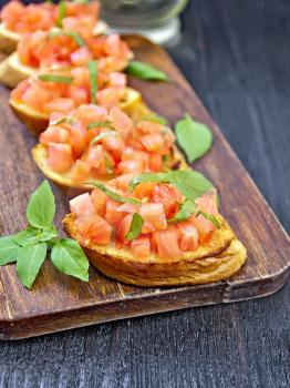Bruschetta with tomatoes and basil on a wooden board background