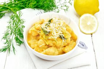 Pumpkin gnocchi with sage, lemon, cheese and butter in a bowl, napkin on wooden board background